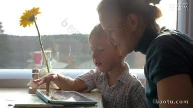 妈妈和小儿子坐在火车<strong>靠窗</strong>的<strong>桌子</strong>旁，孩子在用平板电脑和他们聊天